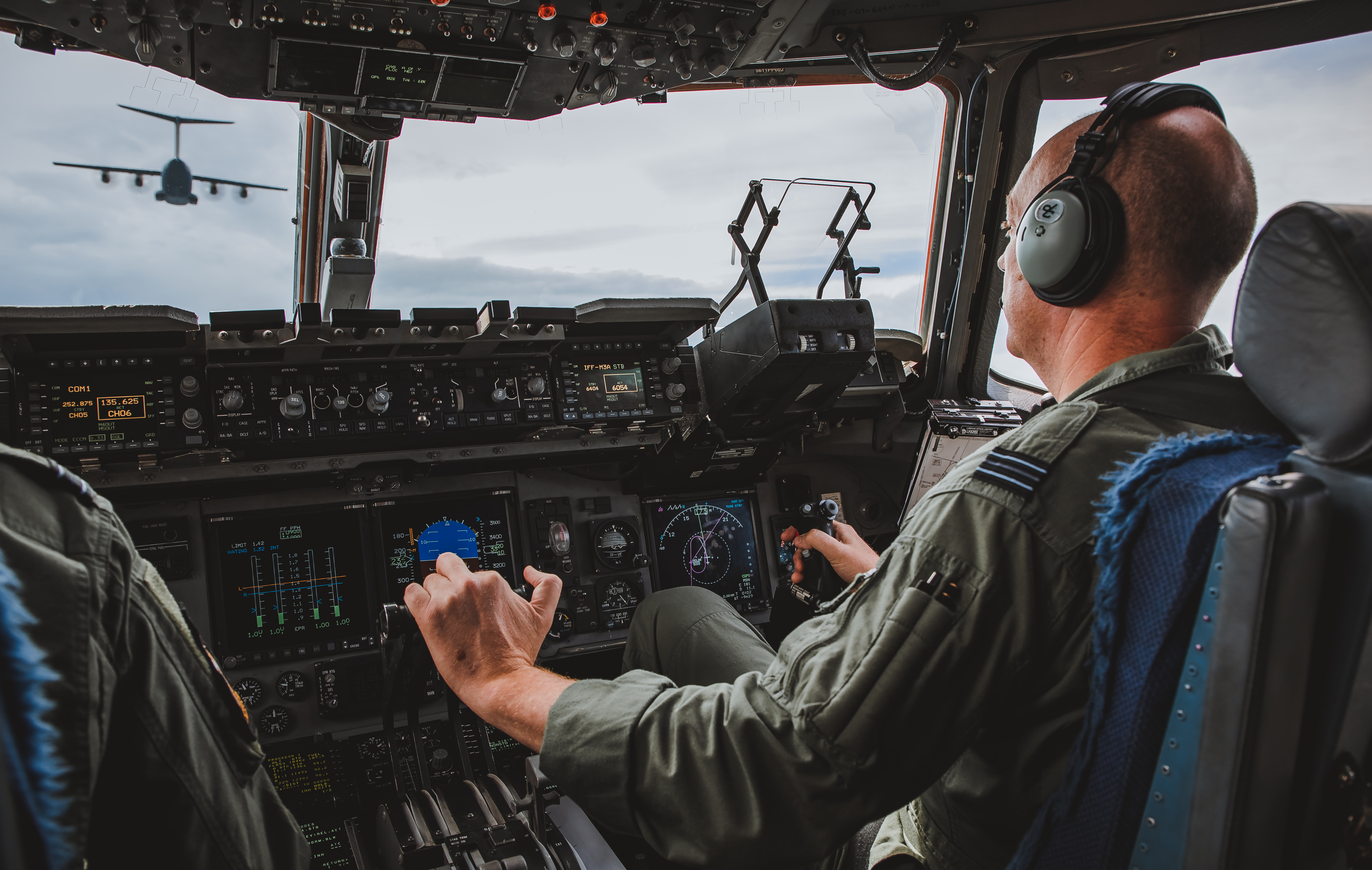 Pilots in the cockpit look out to another aircraft in flight.